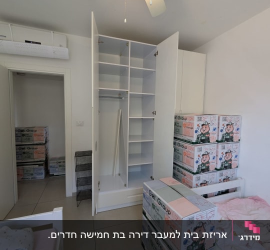 קרטונים ארוזים ומסודרים בחדר ילדים לצד ארון בגדים פתוח